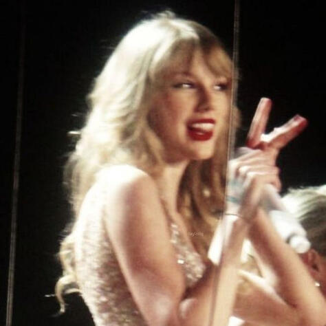 taylor swift at a concert, doing a peace sign